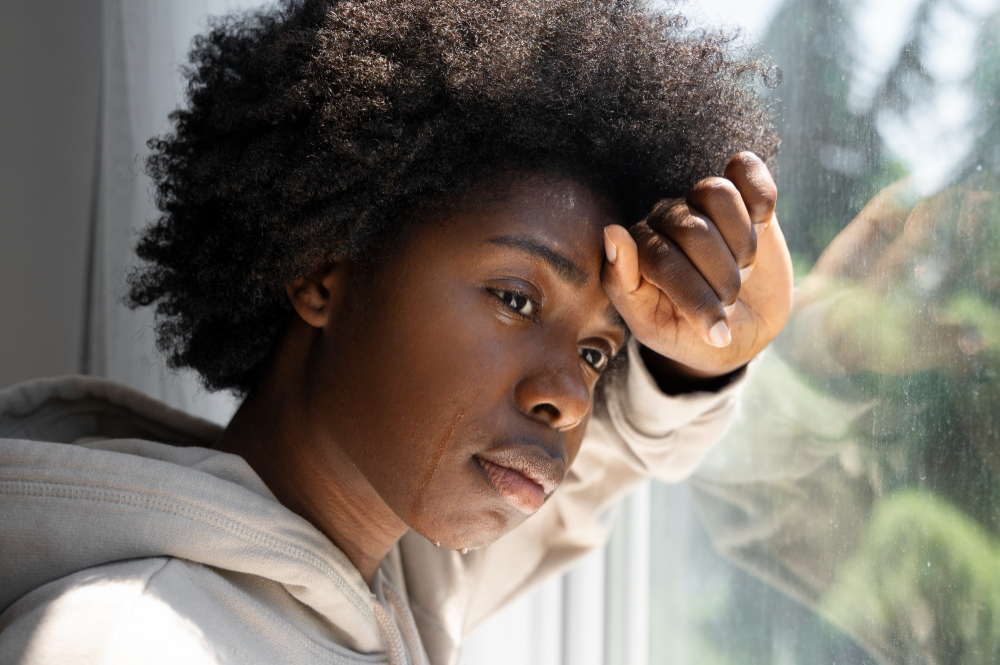 Femme en situation de vulnérabilité émotionnelle regardant par la fenêtre – santé mentale et solitude